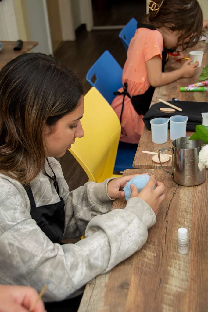 A parent shaping soft blue coloring wax by hand