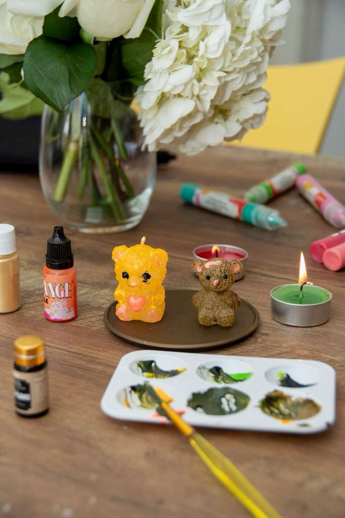 Two finished bear candles beside a wet paint palette