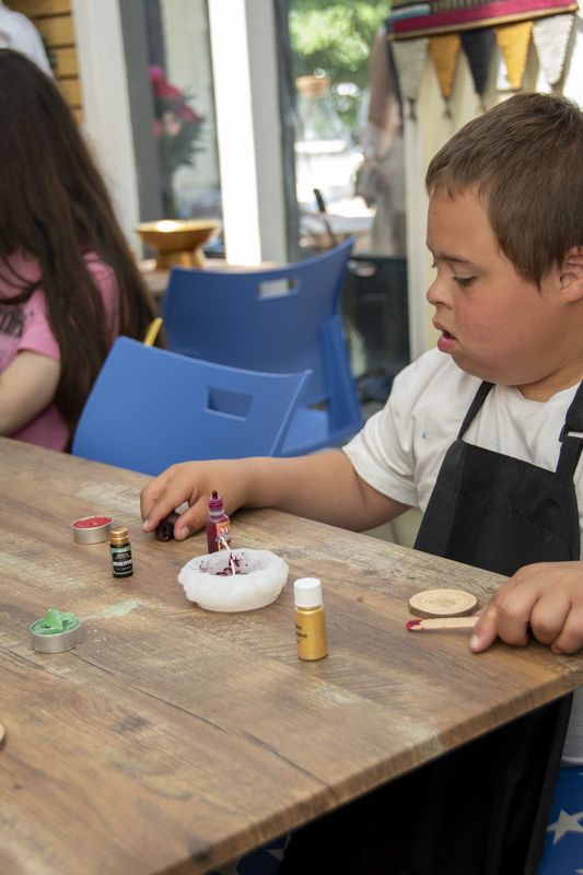 A boy adding colour to his finished candle